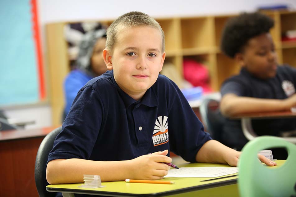 student in classroom smiling at camera