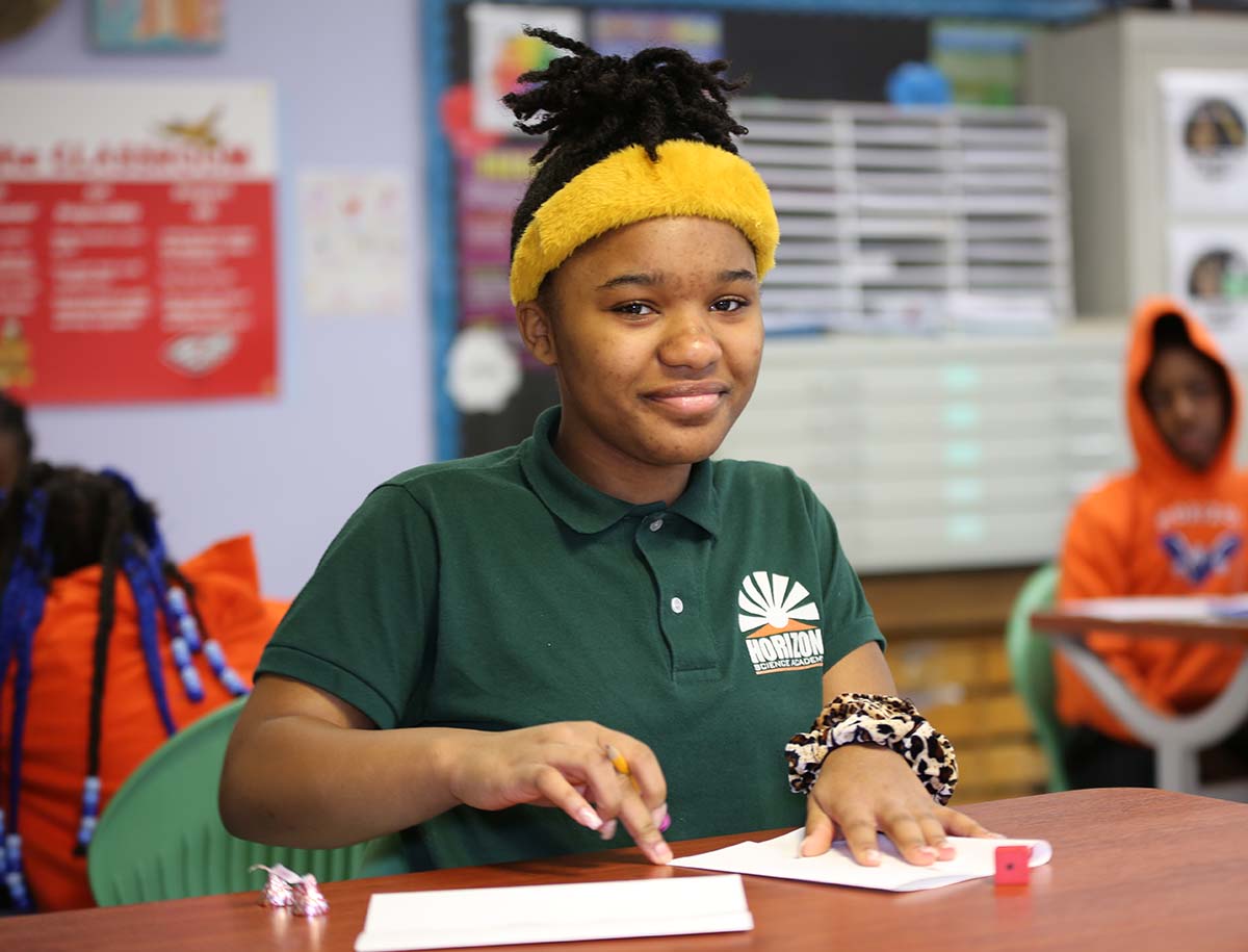 Elementary student smiling and posing together in a classroom.