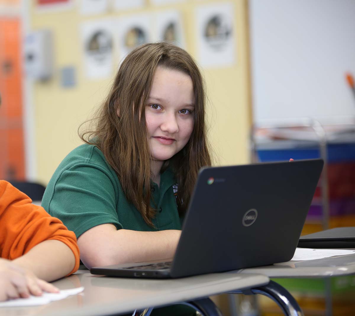 Student working on a notebook in a classroom.